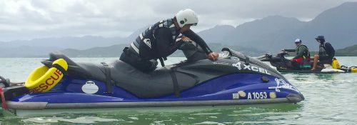 instructor on a jet ski in the ocean with mountains in the background