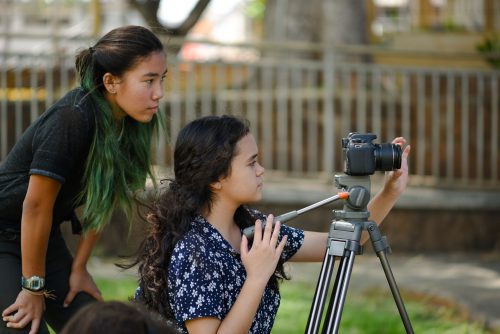 Young girls in the process of filming and adjusting camera.