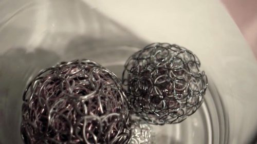 Treasure or Trouble: Polymetallic Nodules I, II, VIII-X knitted metal by Michelle Schwengel-Regala; Copper, aluminum, steel, brass, and seawater in readymade object (glass)