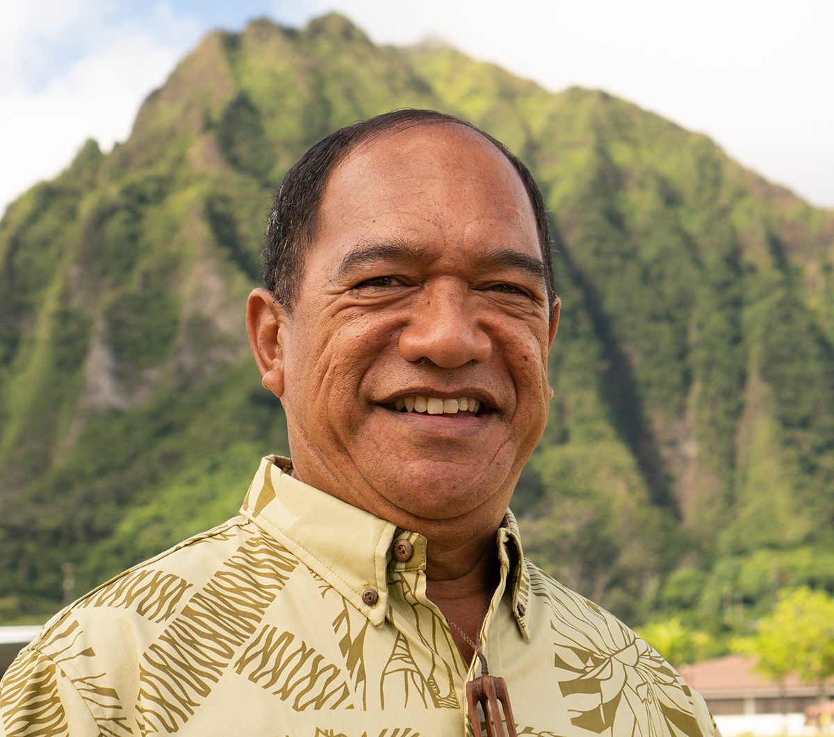 Kimo Adams standing with Koolau mountains behind him in the sun